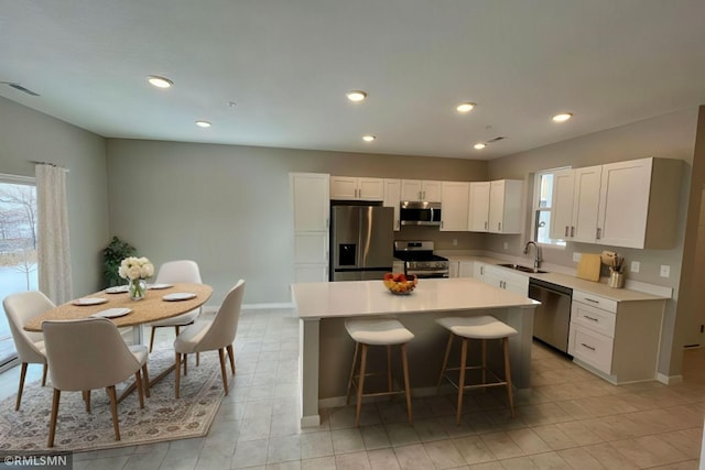 kitchen featuring a wealth of natural light, appliances with stainless steel finishes, a kitchen island, and a sink