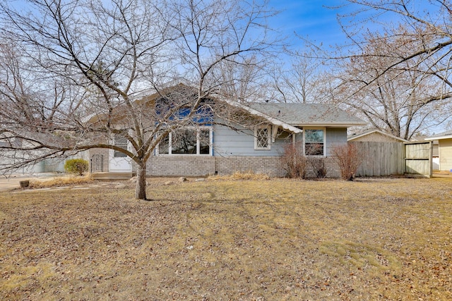 view of front of home featuring a garage, brick siding, and fence