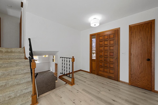 entrance foyer featuring stairway, baseboards, and wood finished floors