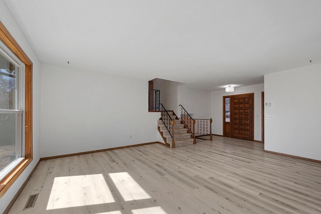 foyer entrance featuring visible vents, baseboards, light wood-style flooring, and stairs