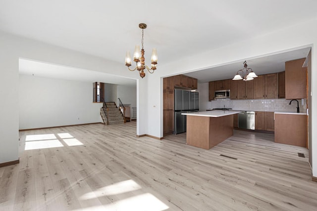 kitchen featuring decorative backsplash, open floor plan, a chandelier, and stainless steel appliances