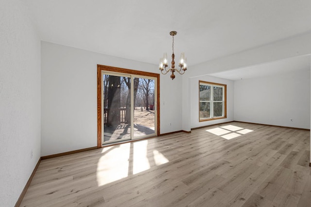 unfurnished dining area featuring baseboards, an inviting chandelier, and wood finished floors