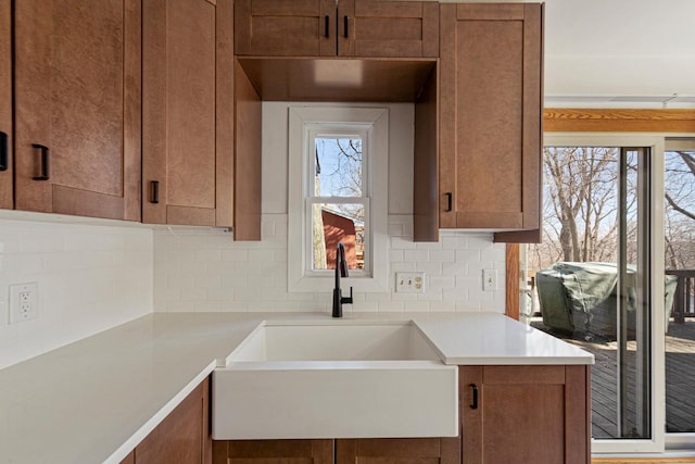 kitchen with decorative backsplash, light countertops, a healthy amount of sunlight, and a sink