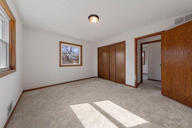 unfurnished bedroom with a closet, visible vents, carpet flooring, and baseboards