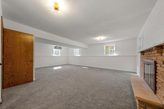 below grade area with carpet flooring, a brick fireplace, a textured ceiling, and baseboards