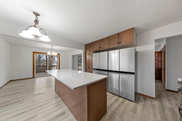 kitchen with a center island, decorative light fixtures, light countertops, light wood-style floors, and a notable chandelier