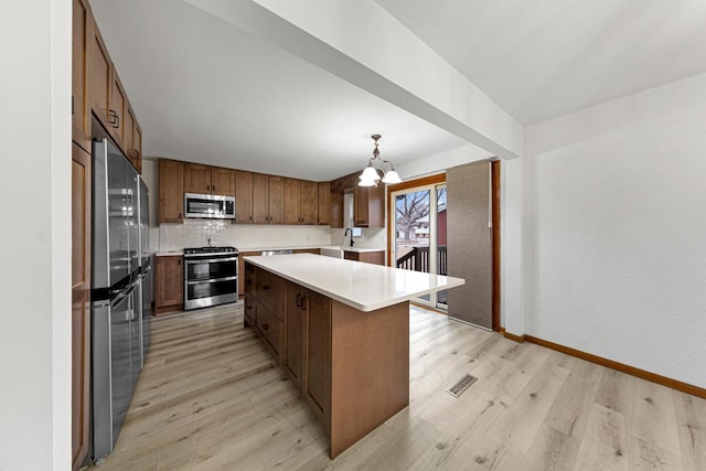 kitchen with light wood-style flooring, stainless steel appliances, light countertops, decorative backsplash, and a chandelier