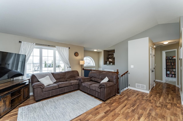 living room with visible vents, lofted ceiling, baseboards, and light wood finished floors