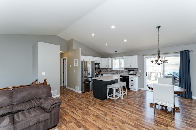 living room featuring lofted ceiling, recessed lighting, light wood-style floors, an inviting chandelier, and baseboards