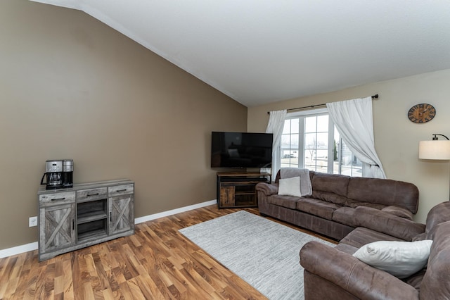 living room with light wood-type flooring, lofted ceiling, and baseboards