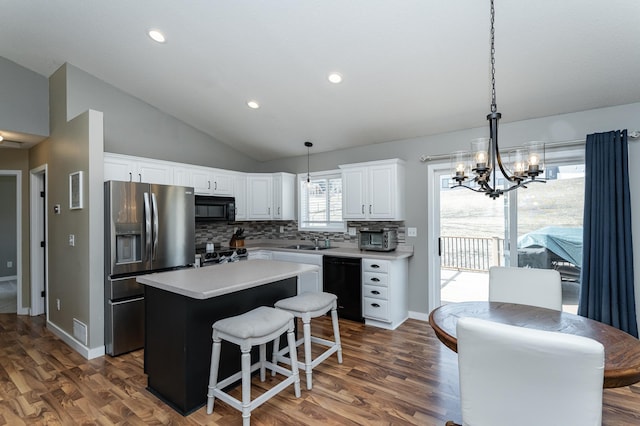 kitchen featuring a kitchen island, lofted ceiling, a sink, black appliances, and a notable chandelier