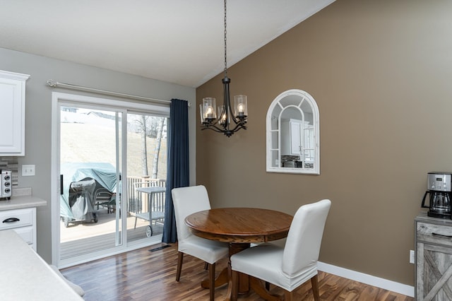 dining area with lofted ceiling, a notable chandelier, wood finished floors, and baseboards