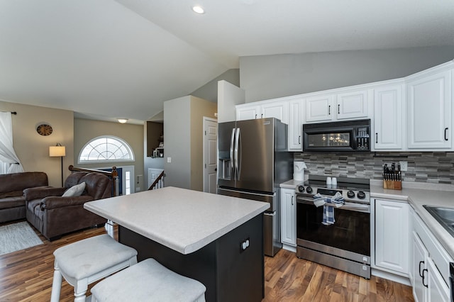 kitchen with open floor plan, a center island, appliances with stainless steel finishes, a breakfast bar area, and lofted ceiling