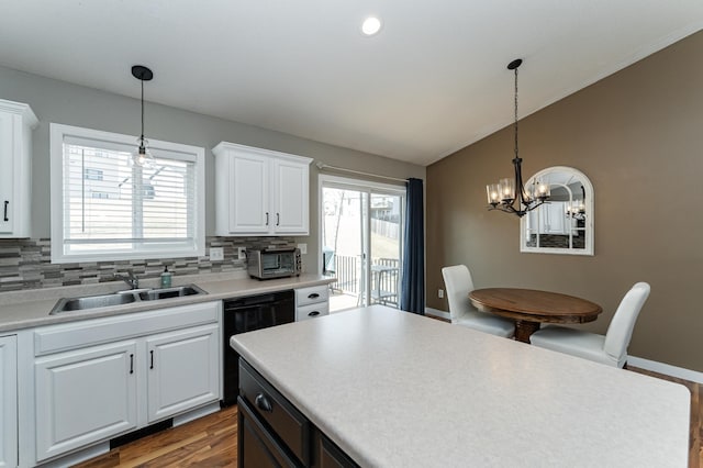 kitchen featuring a sink, white cabinets, dishwasher, a notable chandelier, and tasteful backsplash