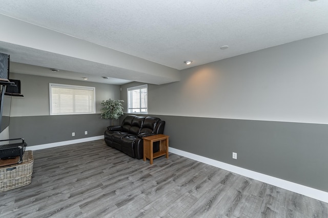 living area featuring wood finished floors, baseboards, and a textured ceiling