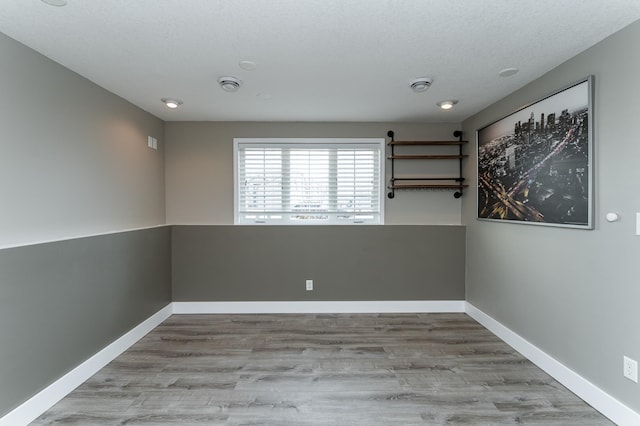 empty room with wood finished floors, baseboards, and a textured ceiling