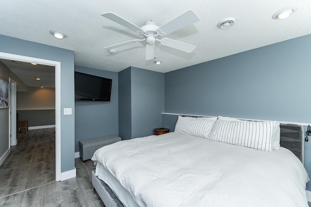 bedroom with wood finished floors, baseboards, visible vents, ceiling fan, and a textured ceiling