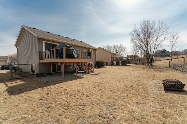 rear view of property featuring a fenced backyard, a fire pit, a deck, and stairs