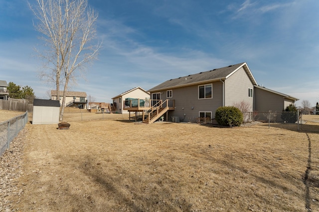 rear view of property with a storage shed, an outbuilding, stairs, and a fenced backyard