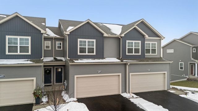 multi unit property with driveway, a shingled roof, a garage, and board and batten siding