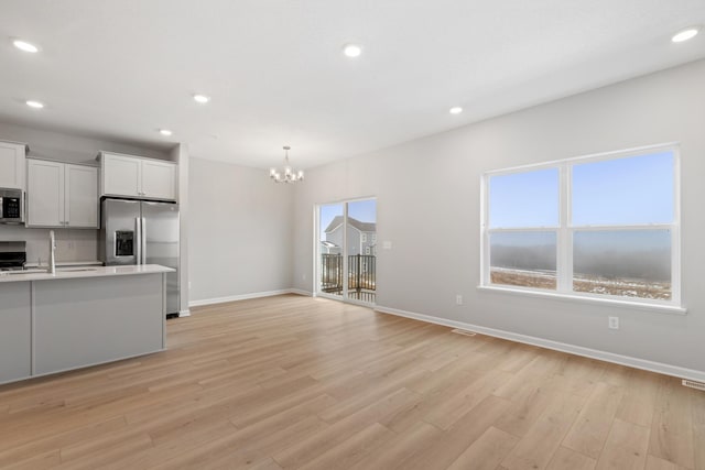 kitchen featuring light wood finished floors, baseboards, light countertops, recessed lighting, and stainless steel appliances