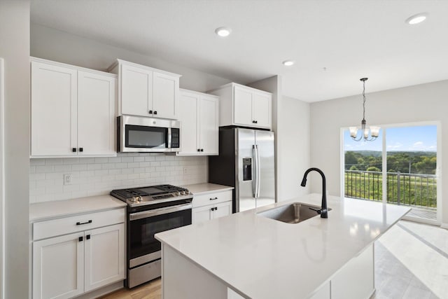 kitchen with light countertops, decorative backsplash, appliances with stainless steel finishes, white cabinets, and a sink