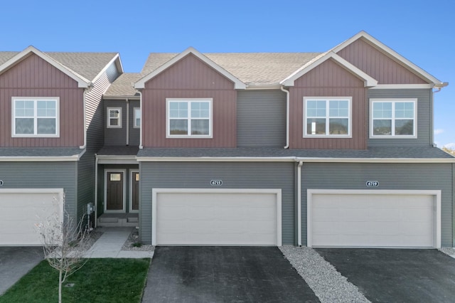 view of property with an attached garage, driveway, and roof with shingles