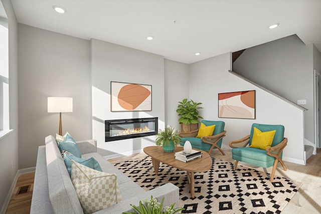 living area featuring visible vents, recessed lighting, wood finished floors, and a glass covered fireplace