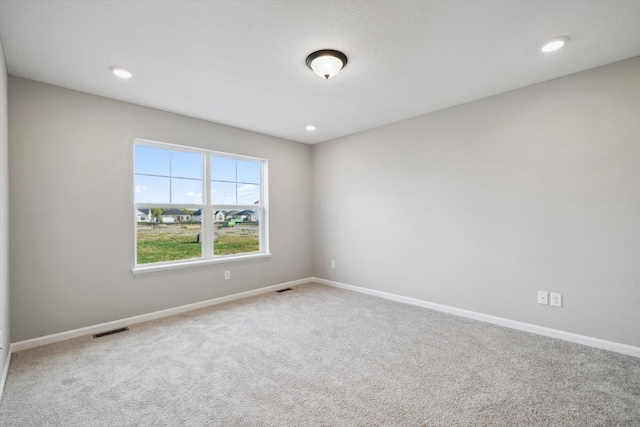 spare room featuring recessed lighting, carpet, visible vents, and baseboards