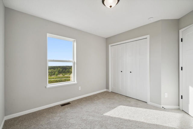 unfurnished bedroom featuring visible vents, carpet floors, baseboards, and a closet