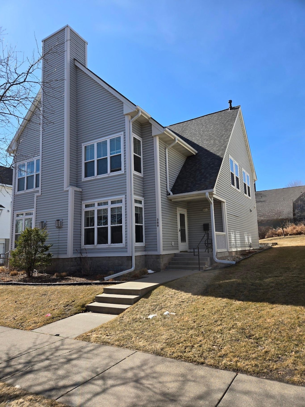 view of front of property featuring a shingled roof, a front lawn, and a chimney