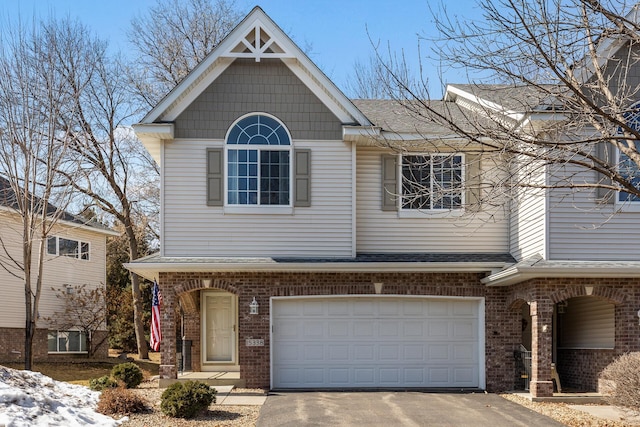 view of front of home featuring brick siding, driveway, and roof with shingles