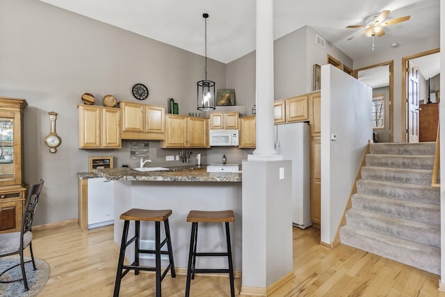 kitchen with white appliances, light brown cabinets, light wood finished floors, high vaulted ceiling, and a kitchen island