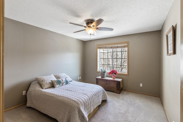 carpeted bedroom with a textured ceiling, a ceiling fan, and baseboards