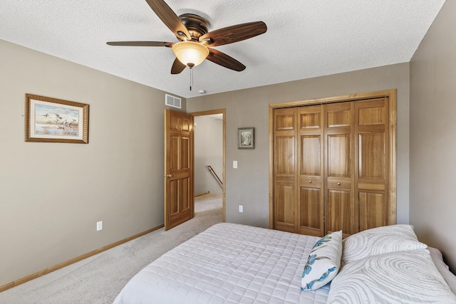 bedroom with visible vents, a textured ceiling, a closet, baseboards, and light colored carpet