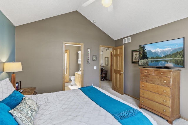 bedroom featuring visible vents, a ceiling fan, ensuite bath, light colored carpet, and vaulted ceiling