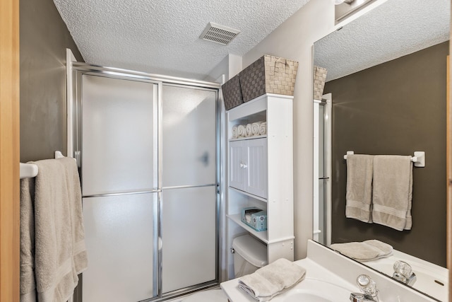 full bathroom with visible vents, a shower stall, a textured ceiling, and toilet