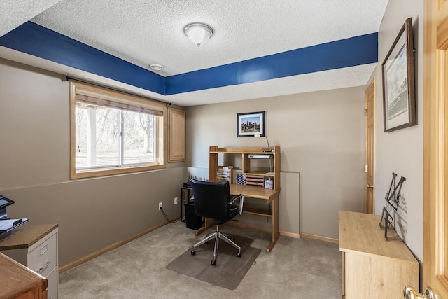 office space with light carpet, a textured ceiling, and baseboards