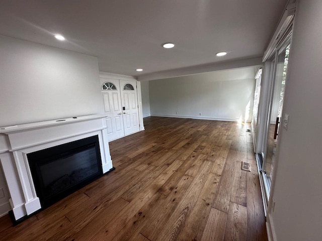 unfurnished living room featuring visible vents, baseboards, recessed lighting, a glass covered fireplace, and dark wood-style flooring