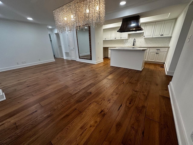 kitchen featuring dark wood-type flooring, open floor plan, ventilation hood, decorative backsplash, and a chandelier