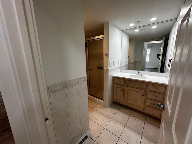 full bathroom featuring tile patterned floors, a shower stall, tile walls, and vanity