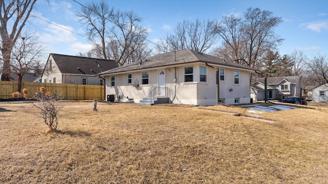 back of house featuring stucco siding, cooling unit, a yard, and fence