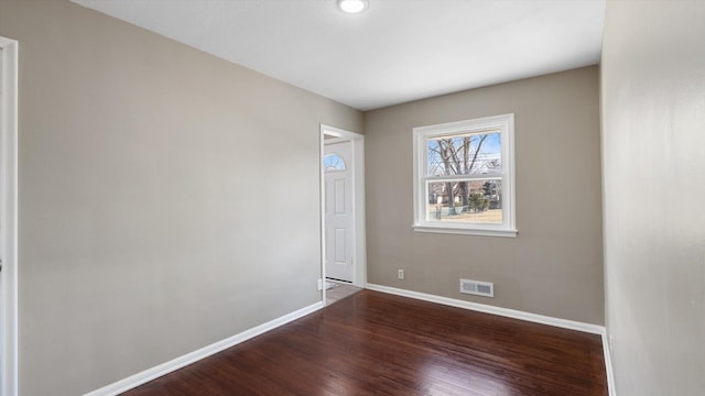 unfurnished room with visible vents, baseboards, and wood finished floors