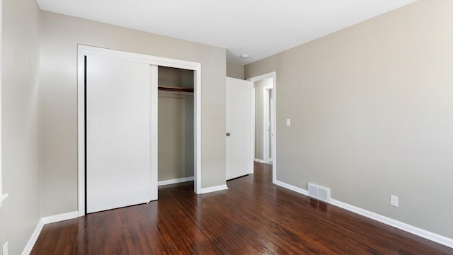 unfurnished bedroom with visible vents, baseboards, a closet, and wood finished floors