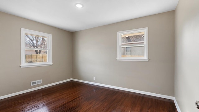 empty room with visible vents, baseboards, and dark wood-style flooring