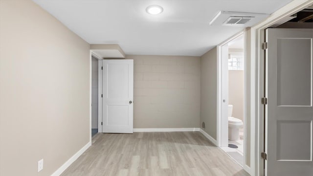 interior space featuring visible vents, baseboards, concrete block wall, and light wood-style floors