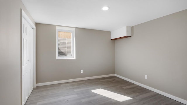 unfurnished bedroom with recessed lighting, wood finished floors, baseboards, and a closet