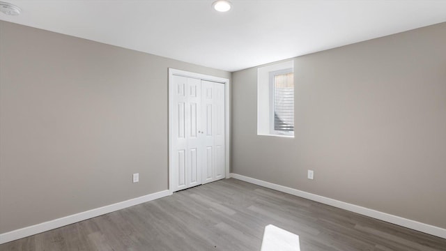 unfurnished bedroom with a closet, baseboards, and wood finished floors