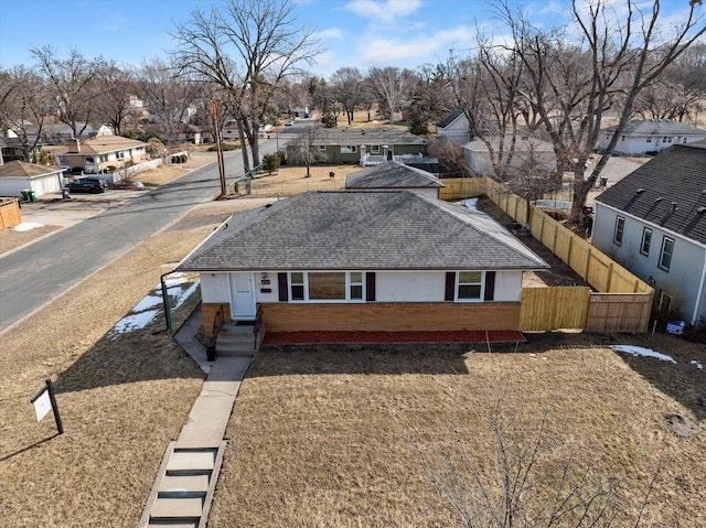 view of front of home with brick siding, a residential view, a shingled roof, and fence