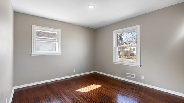 spare room with dark wood finished floors, baseboards, and visible vents